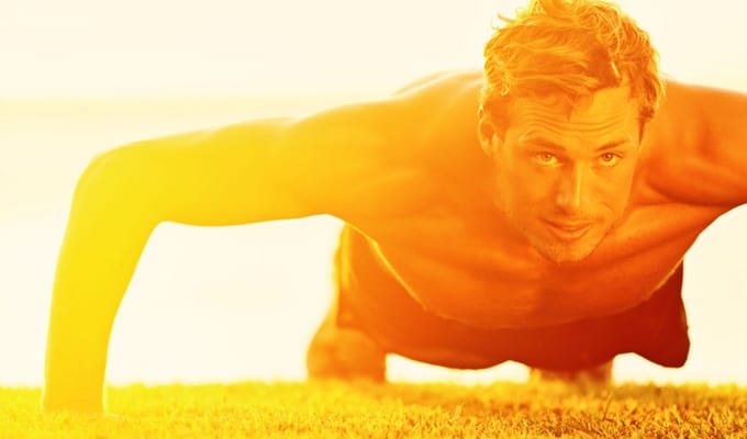 Man performing push-ups outdoors during sunset, showcasing physical fitness and strength training relevant to martial arts and self-defense programs.