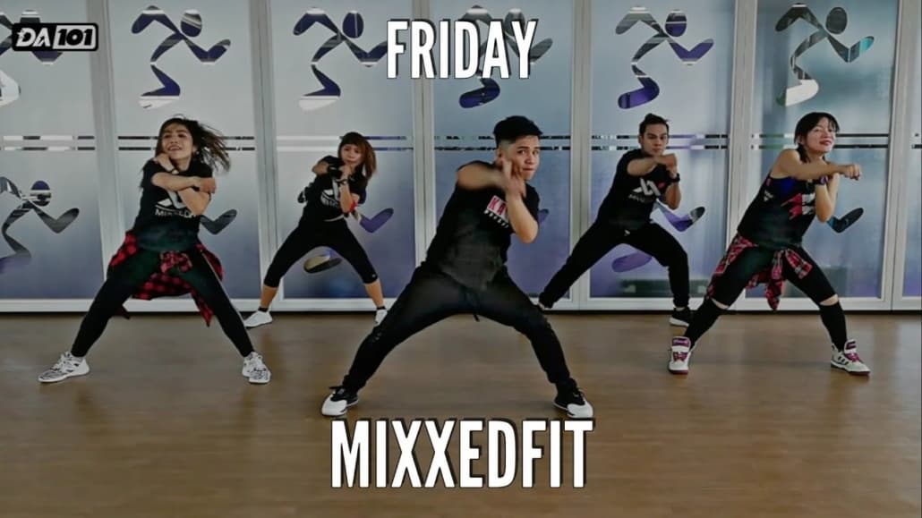 Group fitness class participants performing MixxedFit workout, showcasing energetic movements and camaraderie, with the text "FRIDAY" and "MIXXEDFIT" prominently displayed.